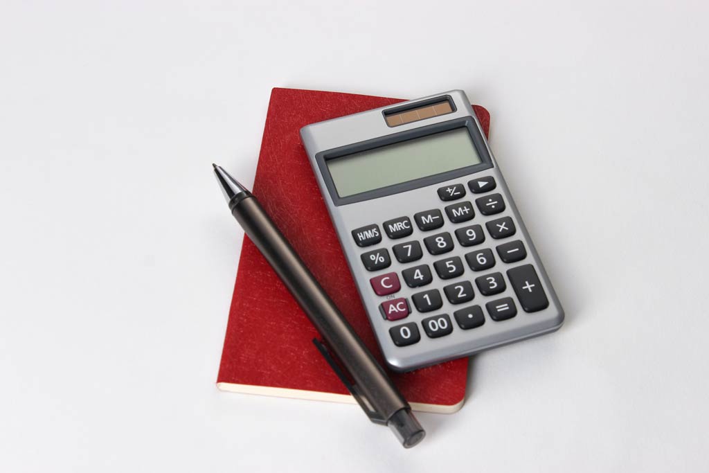 Calculator, pen and notebook for calculation on an office desk