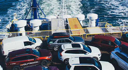 Multiple cars on the deck of a cargo ship being transported to another location