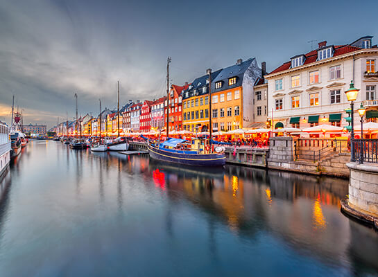 Boats in a Copenhagen canal lined with brightly-colored townhouses