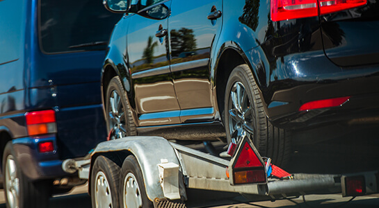 A car secured on an open trailer for towing.
